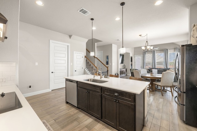 kitchen featuring light wood-style flooring, visible vents, dark brown cabinets, appliances with stainless steel finishes, and a center island with sink