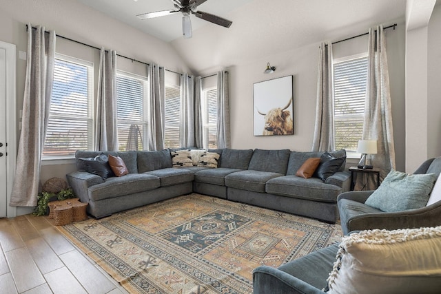 living area featuring ceiling fan, a wealth of natural light, vaulted ceiling, and wood finished floors