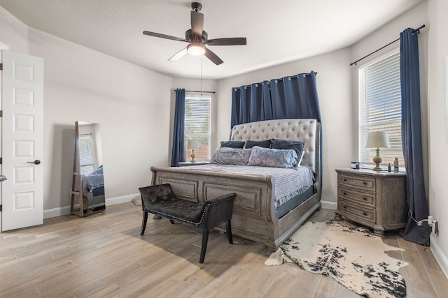 bedroom with a ceiling fan, baseboards, and light wood finished floors