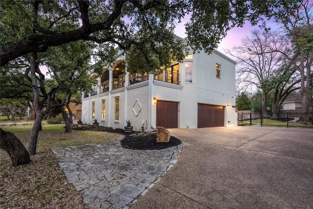 view of front of home with a garage, fence, driveway, and stucco siding