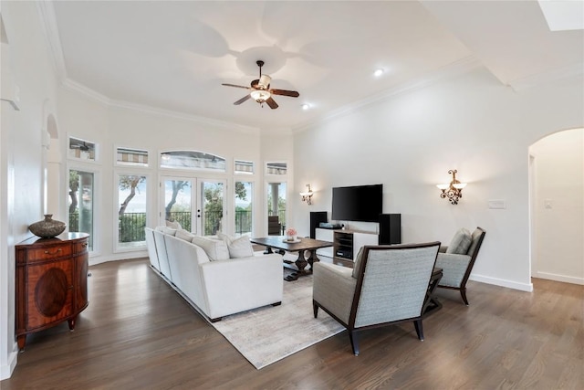 living room with arched walkways, ornamental molding, wood finished floors, and a ceiling fan