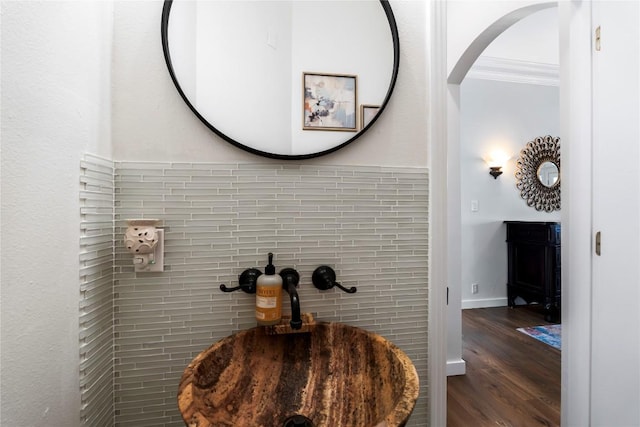 details featuring ornamental molding, a sink, baseboards, and wood finished floors