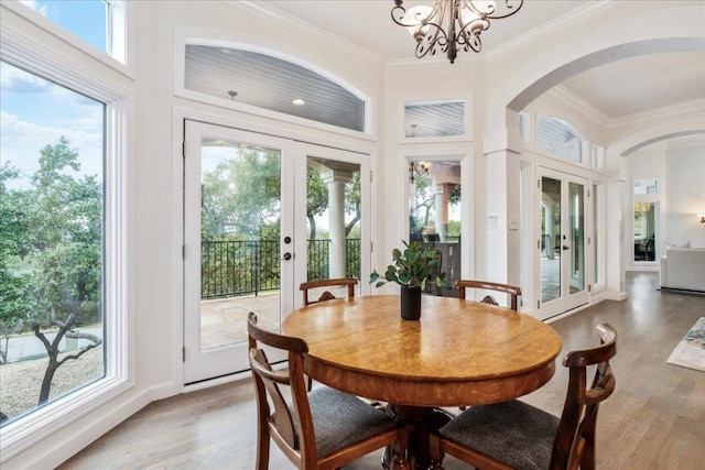 sunroom with a healthy amount of sunlight, an inviting chandelier, arched walkways, and french doors