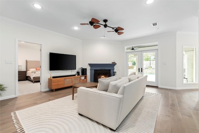 living room with light wood finished floors, french doors, ornamental molding, and visible vents