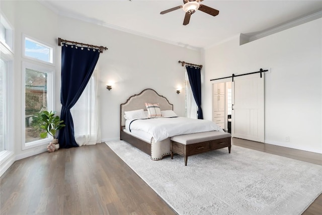 bedroom with a barn door, ornamental molding, and wood finished floors