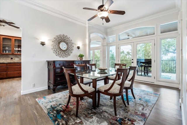 dining space with arched walkways, ceiling fan, ornamental molding, and french doors