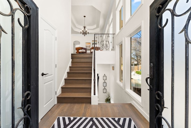 entrance foyer with plenty of natural light, stairway, an inviting chandelier, and wood finished floors