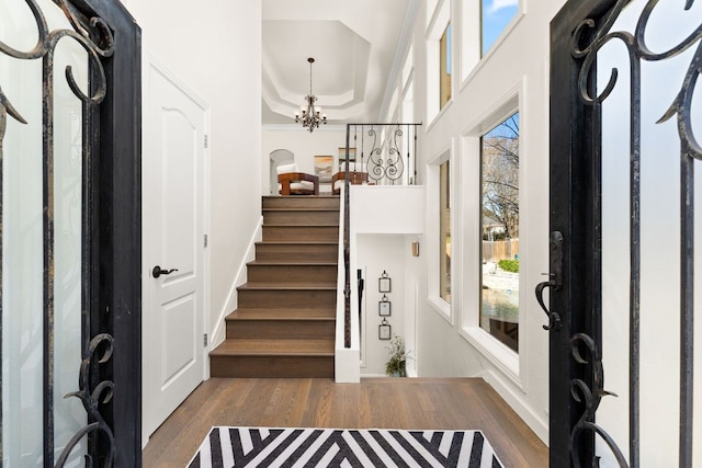 entrance foyer featuring an inviting chandelier, a healthy amount of sunlight, wood finished floors, and stairway