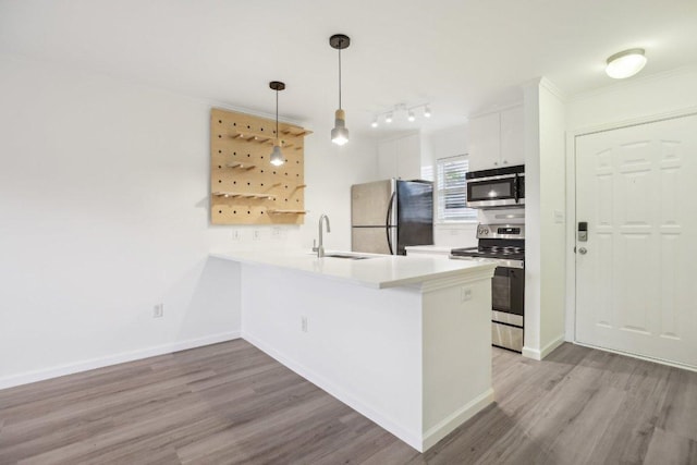 1422 Collier St Unit 102, Austin, TX 78704 - kitchen featuring stainless steel appliances, a sink, wood finished floors, a peninsula, and ornamental molding
