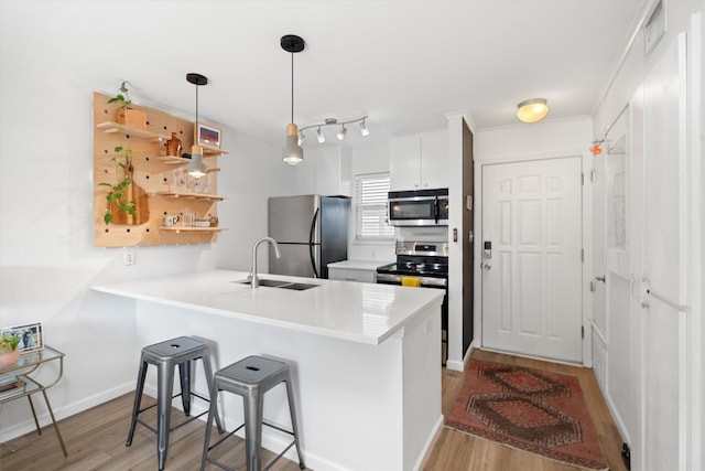 1422 Collier St Unit 102, Austin, TX 78704 - kitchen featuring stainless steel appliances, a sink, light wood-style flooring, and a peninsula