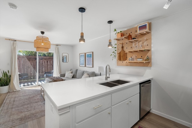 1422 Collier St Unit 102, Austin, TX 78704 - kitchen with a sink, dishwasher, wood finished floors, a peninsula, and decorative light fixtures