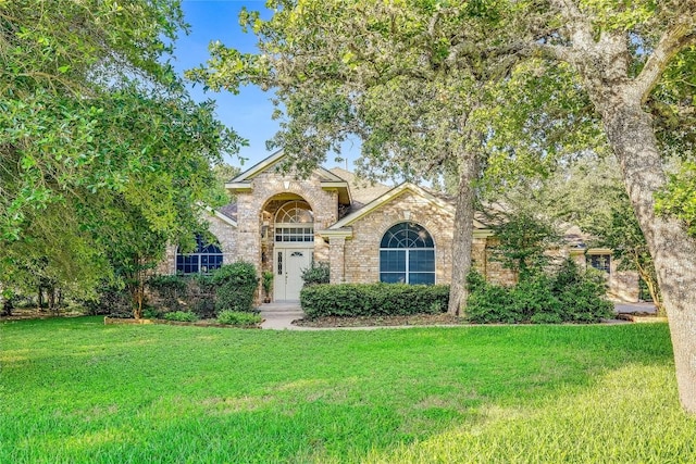 view of front of home featuring stone siding, brick siding, and a front yard