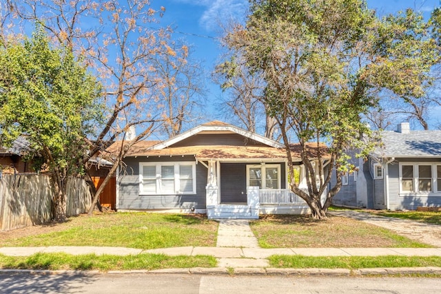 bungalow-style home featuring a porch, fence, and a front lawn