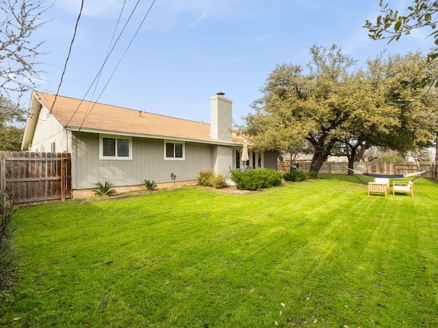 rear view of property with a yard, a chimney, and fence