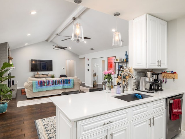 kitchen with lofted ceiling with beams, a peninsula, a sink, open floor plan, and dishwasher