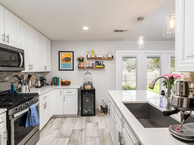 kitchen with stainless steel appliances, beverage cooler, a sink, and backsplash