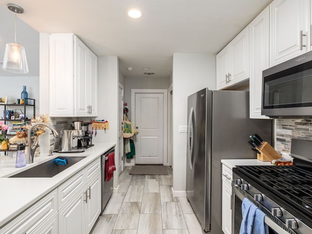 kitchen with stainless steel appliances, tasteful backsplash, light countertops, white cabinets, and a sink