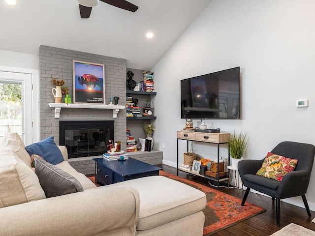 living room featuring vaulted ceiling, dark wood-type flooring, a brick fireplace, and baseboards