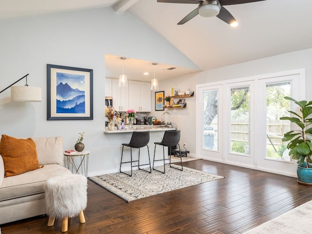 interior space with a breakfast bar area, a peninsula, wood finished floors, white cabinetry, and beam ceiling