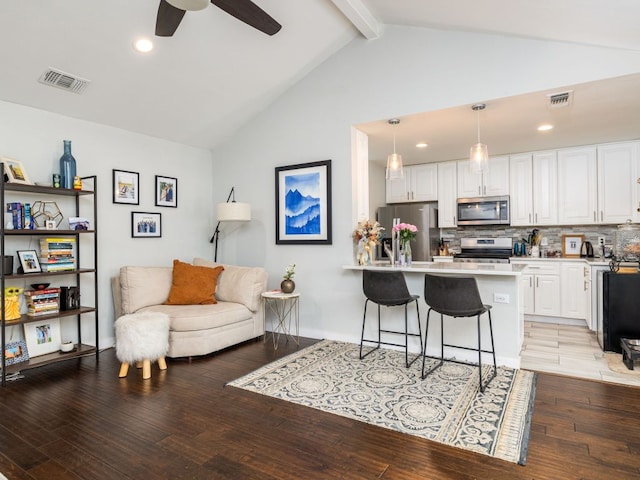 living area featuring lofted ceiling with beams, light wood finished floors, ceiling fan, and visible vents