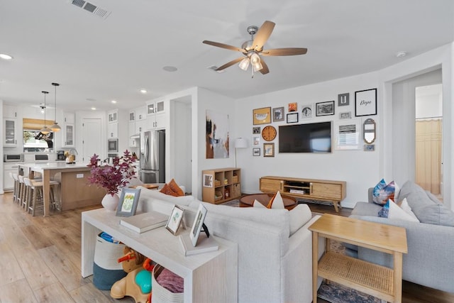 living area featuring light wood-style floors, recessed lighting, visible vents, and a ceiling fan