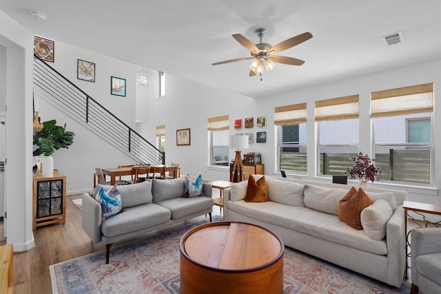 living area with stairs, ceiling fan, visible vents, and hardwood / wood-style flooring