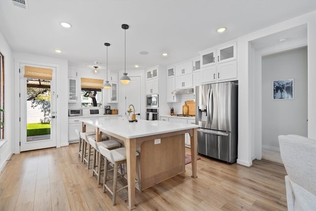 kitchen with light wood-type flooring, a kitchen bar, appliances with stainless steel finishes, and light countertops