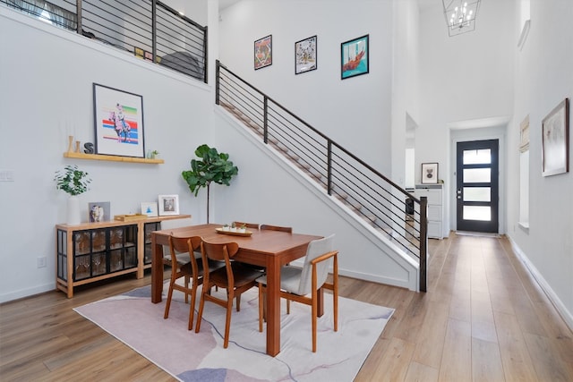 dining area featuring stairs, wood finished floors, a towering ceiling, and a chandelier