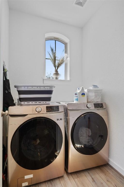 washroom with laundry area, light wood-style flooring, baseboards, and separate washer and dryer