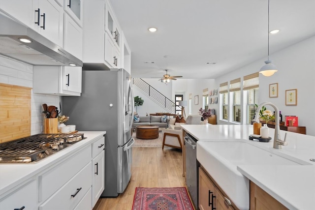 kitchen featuring light countertops, appliances with stainless steel finishes, a sink, and under cabinet range hood