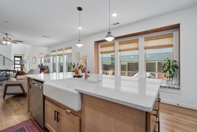 kitchen with light wood-style floors, open floor plan, a sink, and stainless steel dishwasher