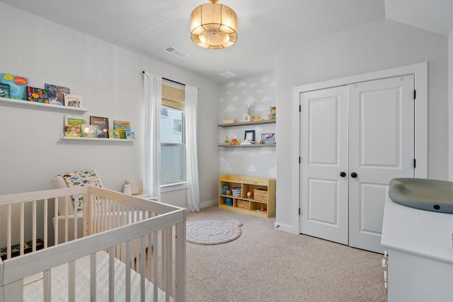 carpeted bedroom with a crib, a closet, visible vents, and baseboards