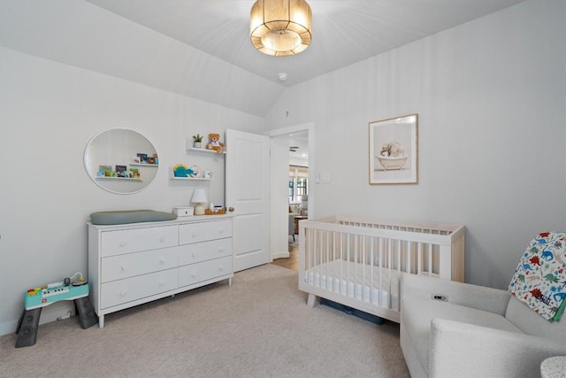 carpeted bedroom featuring lofted ceiling and a nursery area