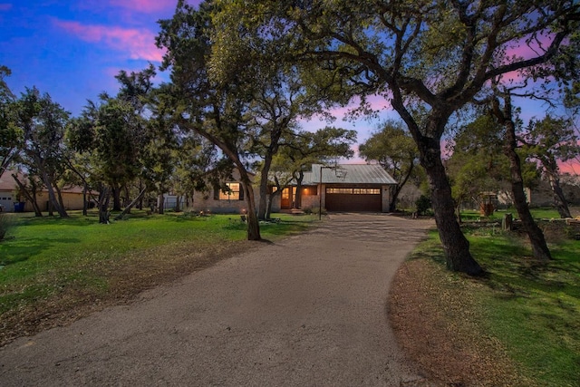 view of front facade featuring brick siding, a front yard, metal roof, a garage, and driveway