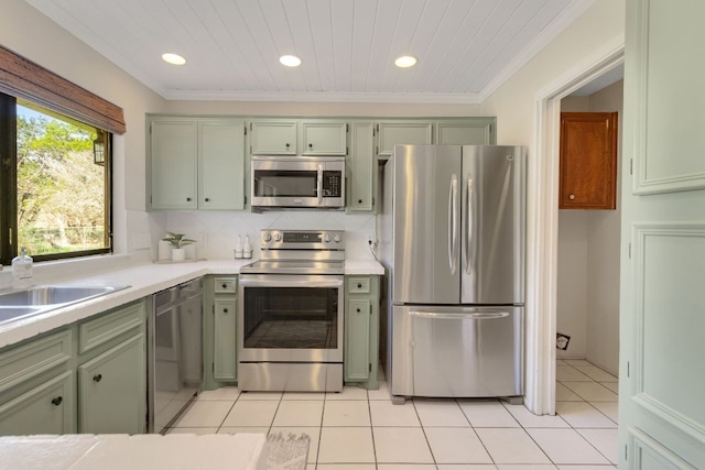 kitchen with stainless steel appliances, light countertops, green cabinets, and tasteful backsplash