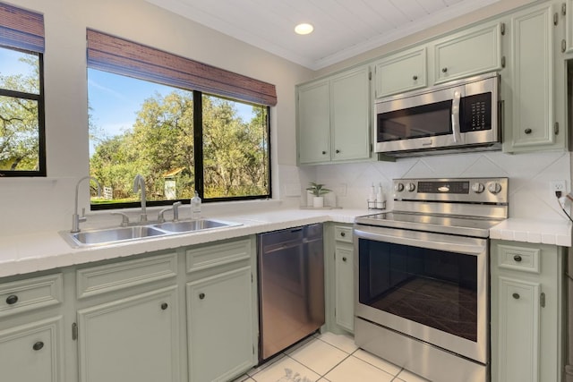 kitchen with appliances with stainless steel finishes, a sink, decorative backsplash, and light tile patterned floors