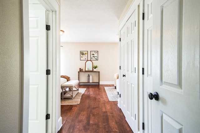 corridor with dark wood-style flooring and baseboards