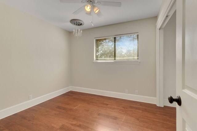 unfurnished bedroom with ceiling fan with notable chandelier, a closet, baseboards, and wood finished floors