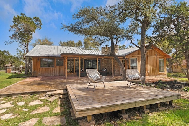 back of property with a chimney, metal roof, and a wooden deck