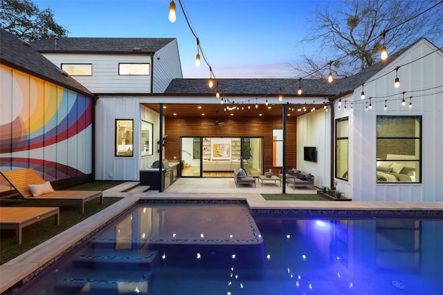 back of house featuring outdoor lounge area, board and batten siding, a ceiling fan, a patio area, and an outdoor pool