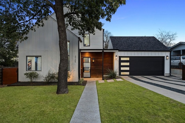 view of front facade with concrete driveway, roof with shingles, an attached garage, and a front lawn