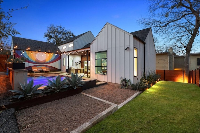 back of house with board and batten siding, a fenced backyard, a lawn, and a hot tub