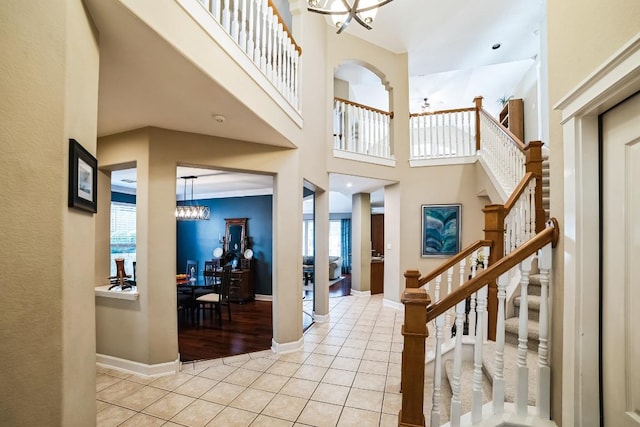 foyer entrance with baseboards, stairs, a high ceiling, a notable chandelier, and light tile patterned flooring