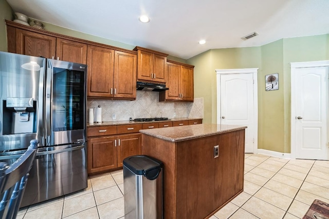 kitchen with gas stovetop, light tile patterned floors, visible vents, under cabinet range hood, and stainless steel fridge with ice dispenser