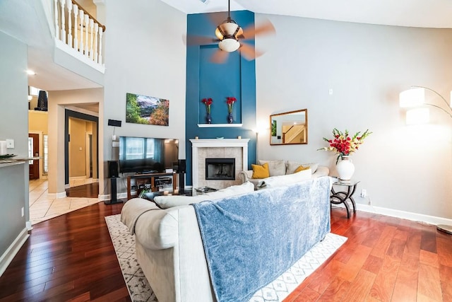 living room with a towering ceiling, light wood finished floors, a fireplace, and baseboards