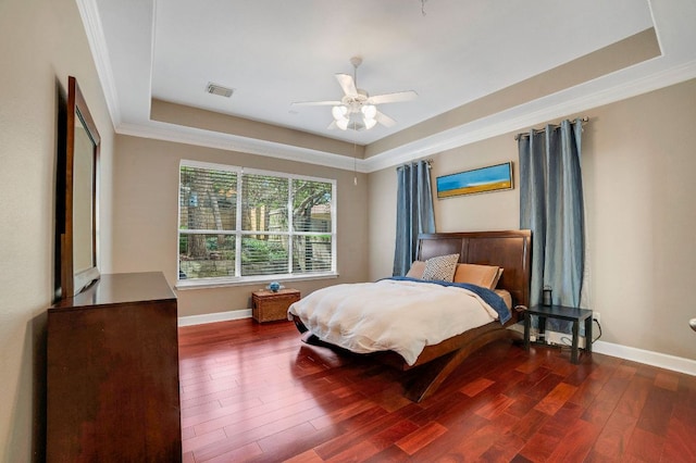 bedroom with hardwood / wood-style flooring, visible vents, baseboards, and a raised ceiling