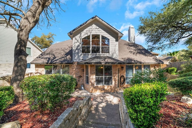 view of front of home featuring roof with shingles, a chimney, fence, and brick siding