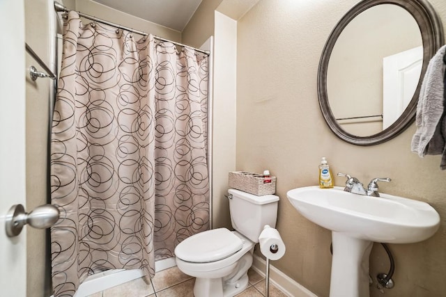 full bath featuring toilet, a shower with curtain, baseboards, and tile patterned floors