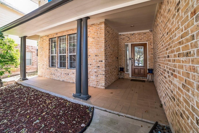 property entrance with covered porch and brick siding