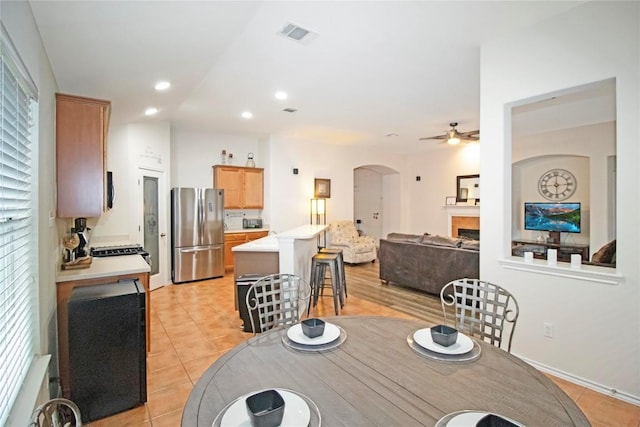 dining space featuring arched walkways, light tile patterned flooring, recessed lighting, a fireplace, and visible vents